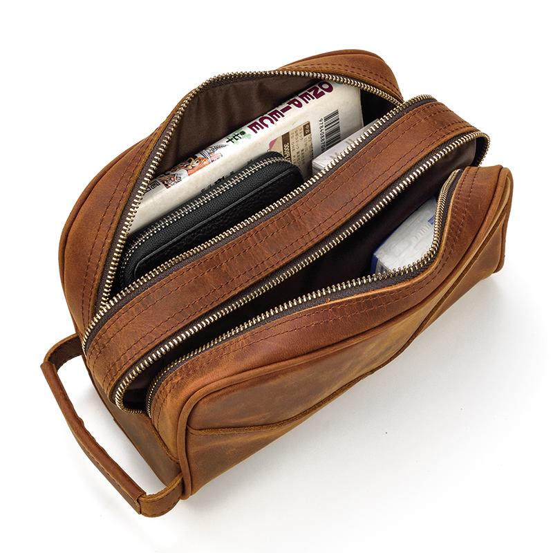 Brown leather toilet bag with multiple zippers on a white background
