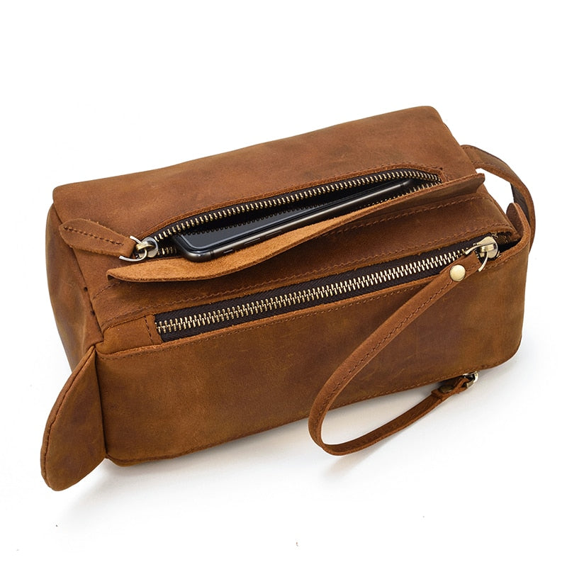 Brown leather toiletry bag with a shoulder strap on a white background