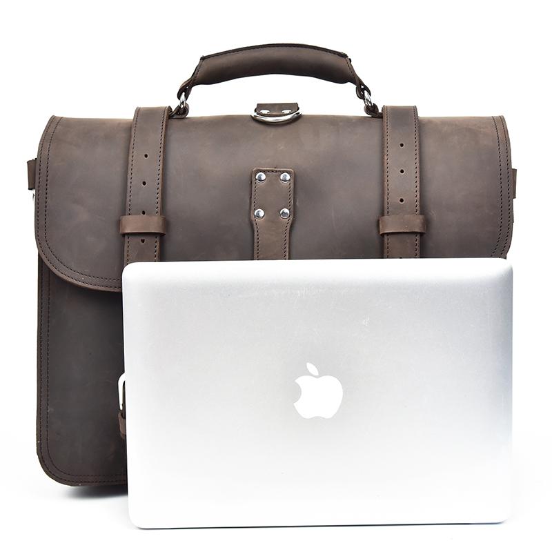 Brown leather briefcase next to a silver laptop on a white background