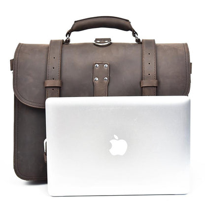 Brown leather briefcase next to a silver laptop on a white background