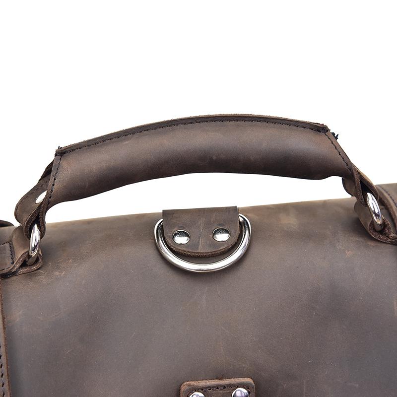 Close-up of a brown leather bag handle with metal rings on a white background