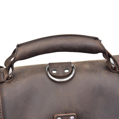 Close-up of a brown leather bag handle with metal rings on a white background