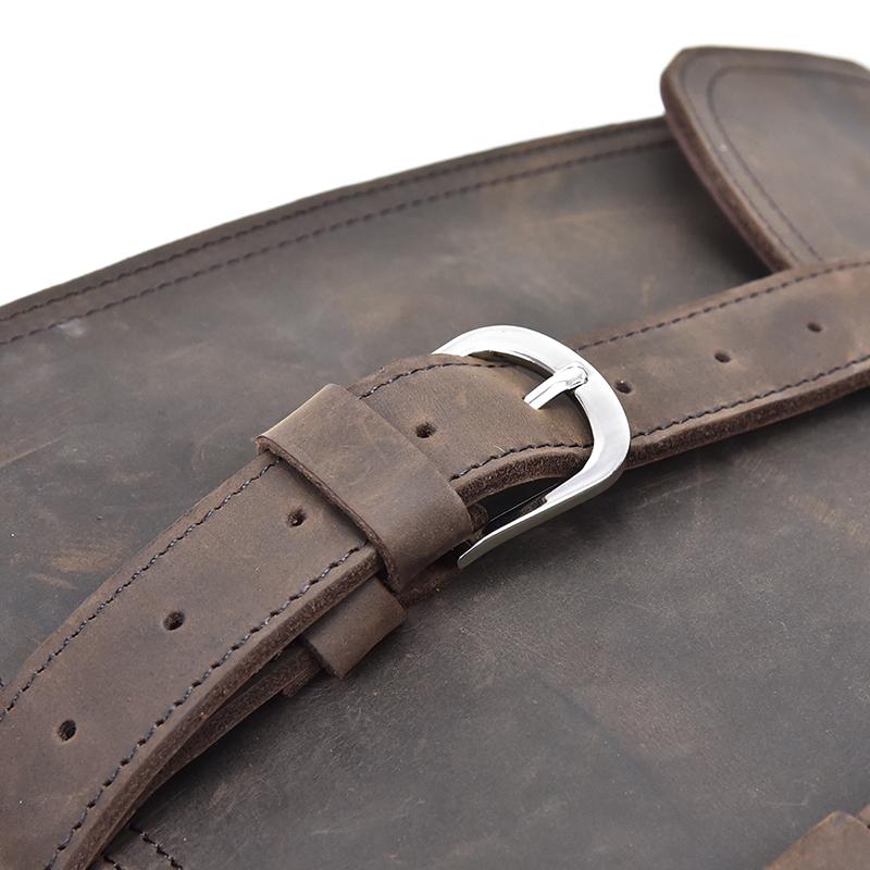 Close-up of a brown leather strap with a silver buckle on a textured surface.