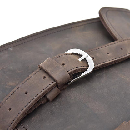 Close-up of a brown leather strap with a silver buckle on a textured surface.