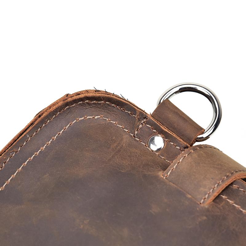 Close-up of a brown leather bag with a metal ring on a white background