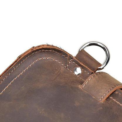 Close-up of a brown leather bag with a metal ring on a white background