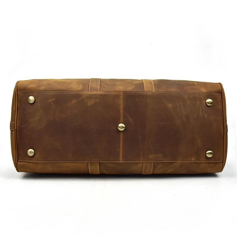Brown leather bag with gold studs on bottom of duffle, shown on a white background