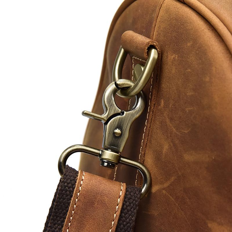 Close-up of a brown leather bag with a gold clasp and strap on a white background