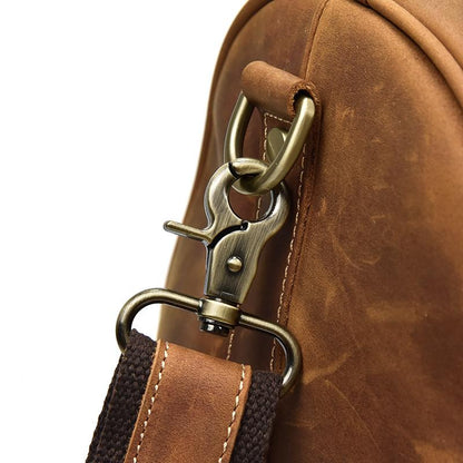 Close-up of a brown leather bag with a gold clasp and strap on a white background