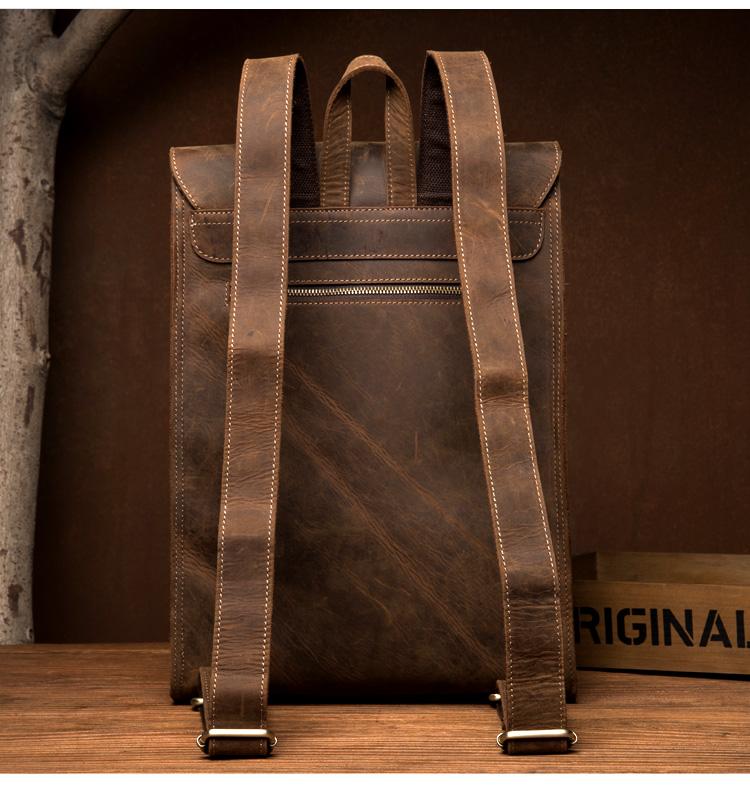Brown leather backpack on a wooden surface with a dark brown background