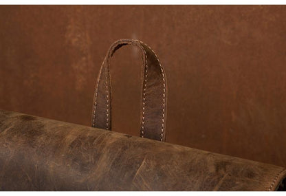 Close-up of a brown leather bag with visible stitching on a matching brown background