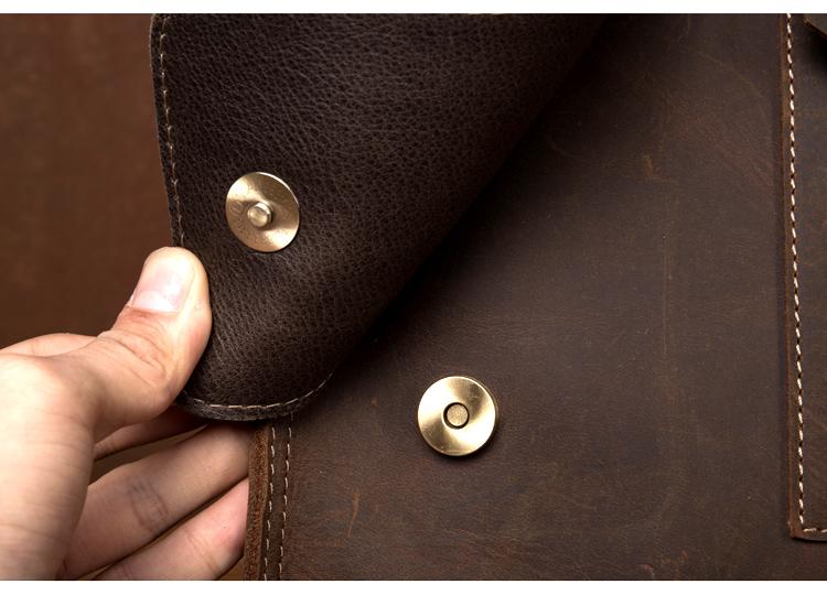 Close-up of a brown leather jacket with gold buttons and a hand touching the fabric.