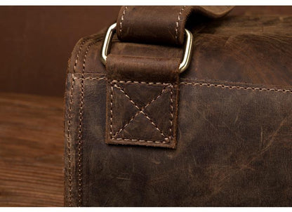 Close-up of a brown leather bag with stitching detail on a wooden surface