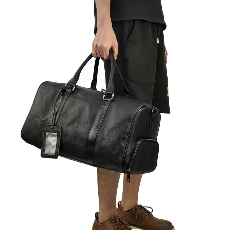 Person holding a black leather duffel bag on a white background