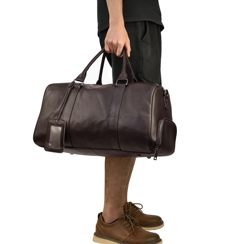 Person holding a brown leather duffel bag on a white background