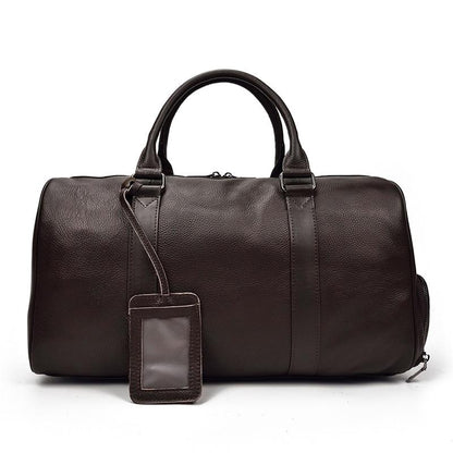 Brown leather duffel bag with a matching luggage tag on a white background