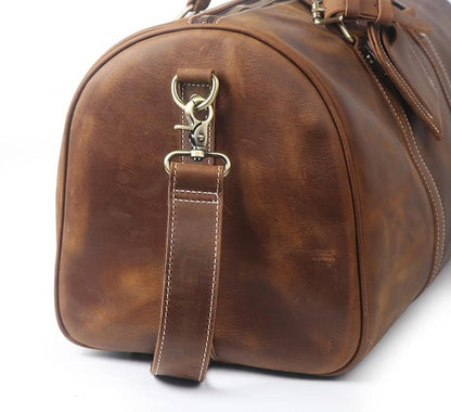 Brown leather duffel bag with a strap on a white background