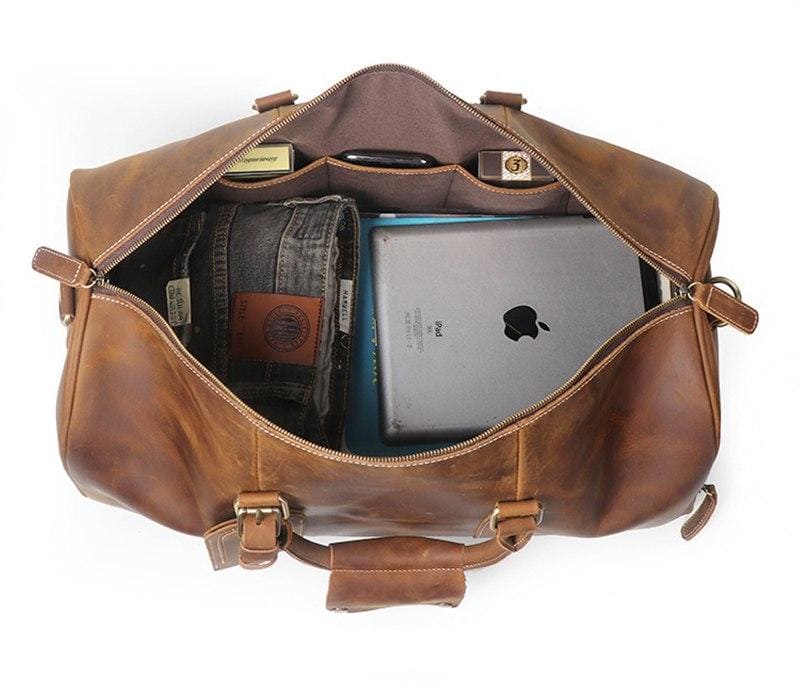 Brown leather duffel bag with items inside on a white background