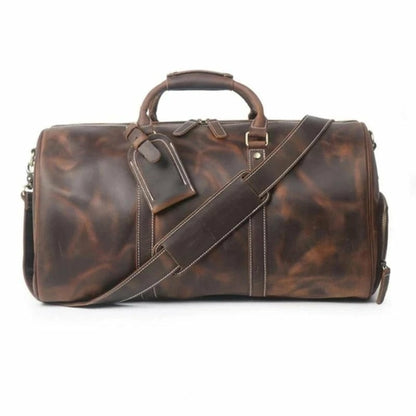 Brown leather duffel bag with a shoulder strap on a white background