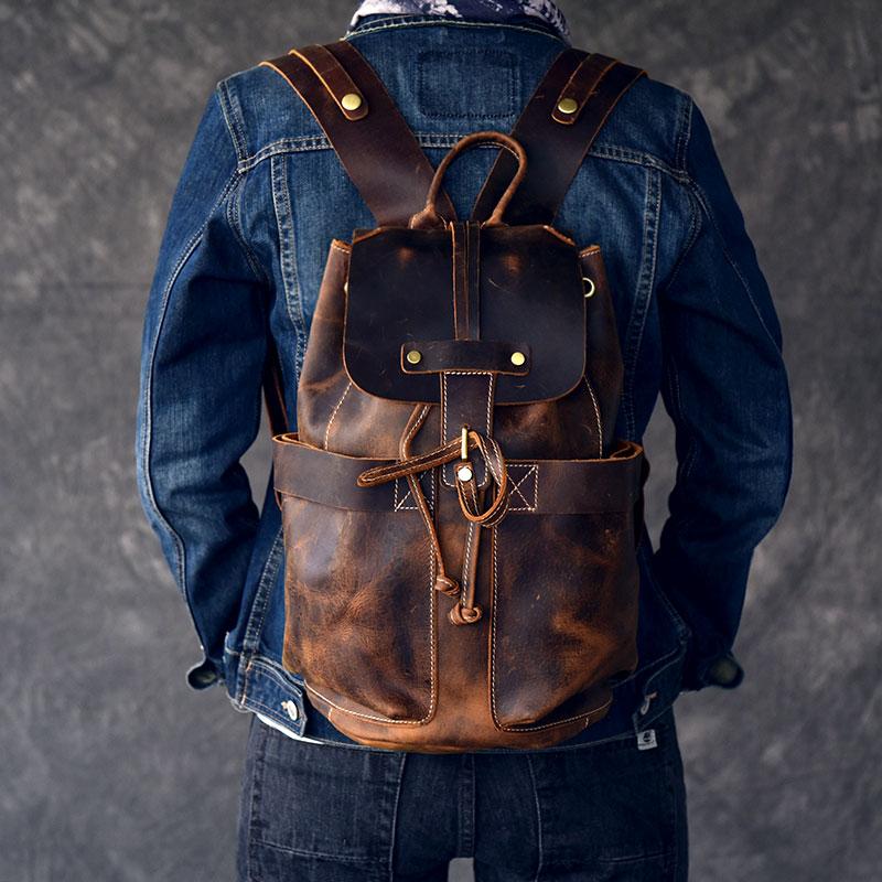 Person wearing a brown leather backpack with a denim jacket on a gray background