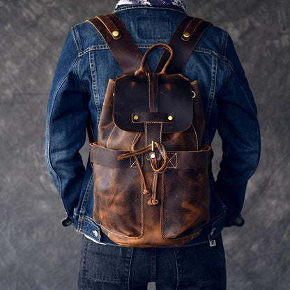 Person wearing a brown leather backpack with a denim jacket on a gray background