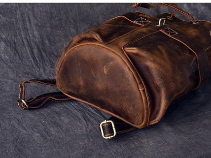 Brown leather duffel bag on a dark textured surface