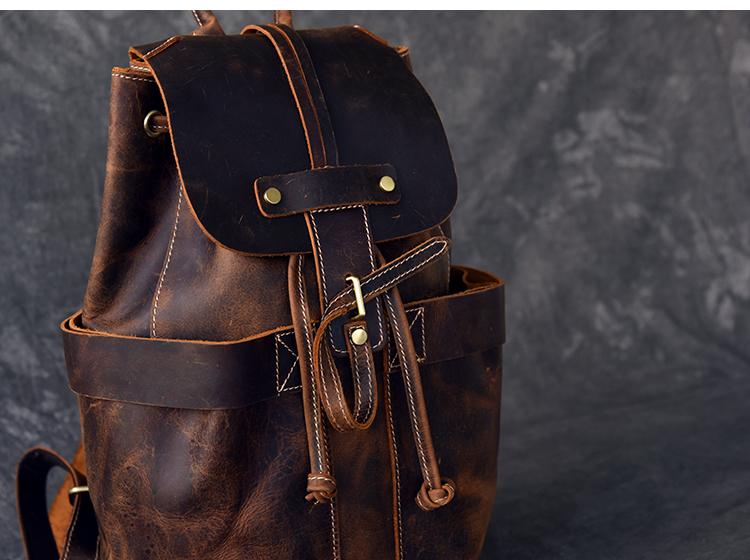 Brown leather backpack with gold accents on a dark background