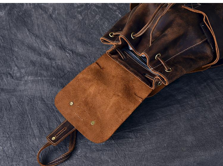 Brown leather pouch with drawstring on a dark textured fabric background